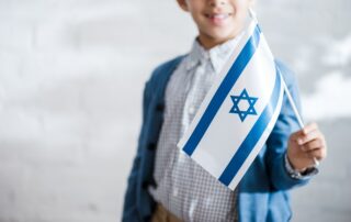 cropped view of smiling jewish boy holding flag of israel
